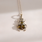 A silver amber beetle necklace with two oval amber-colored gemstones on the front and a smaller round amber stone above, hanging from a silver ball chain on a light background.