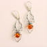 Silver sider earrings with amber beads on a light pink background