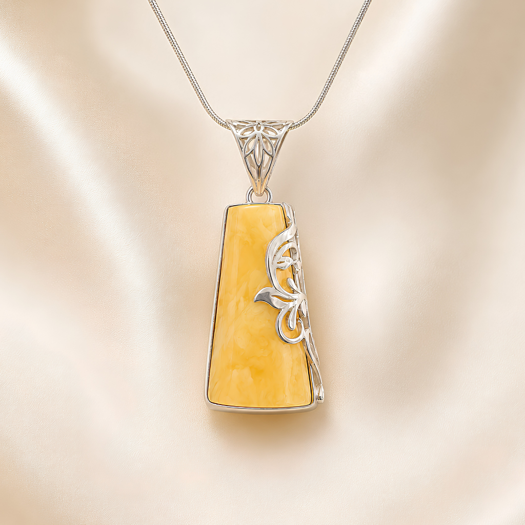 butterscotch amber necklace with silver floral design on a beige background