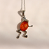 A silver frog pendant necklace featuring a polished orange-red amber cabochon in the center, suspended from a silver chain against a plain light background.