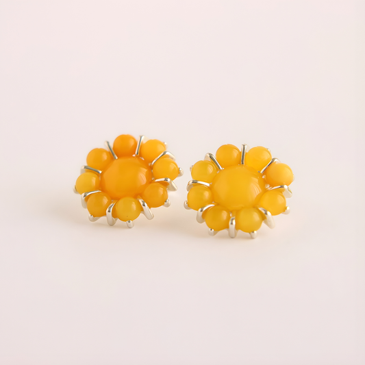 Pair of yellow flower earrings on a light beige background