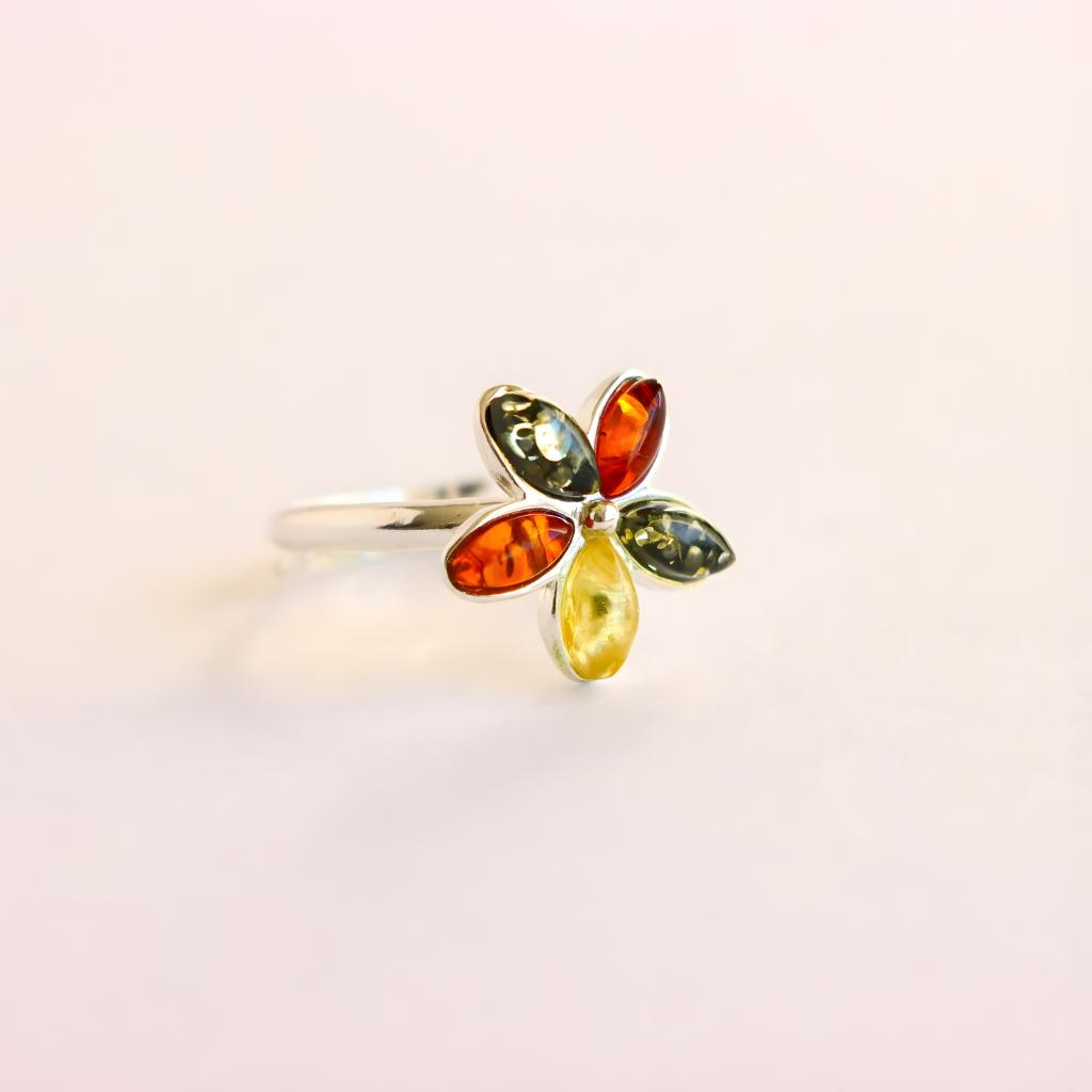 Multicolored gemstone amber ring on a light pink background
