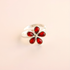 Silver amber ring with red gemstones on a beige background