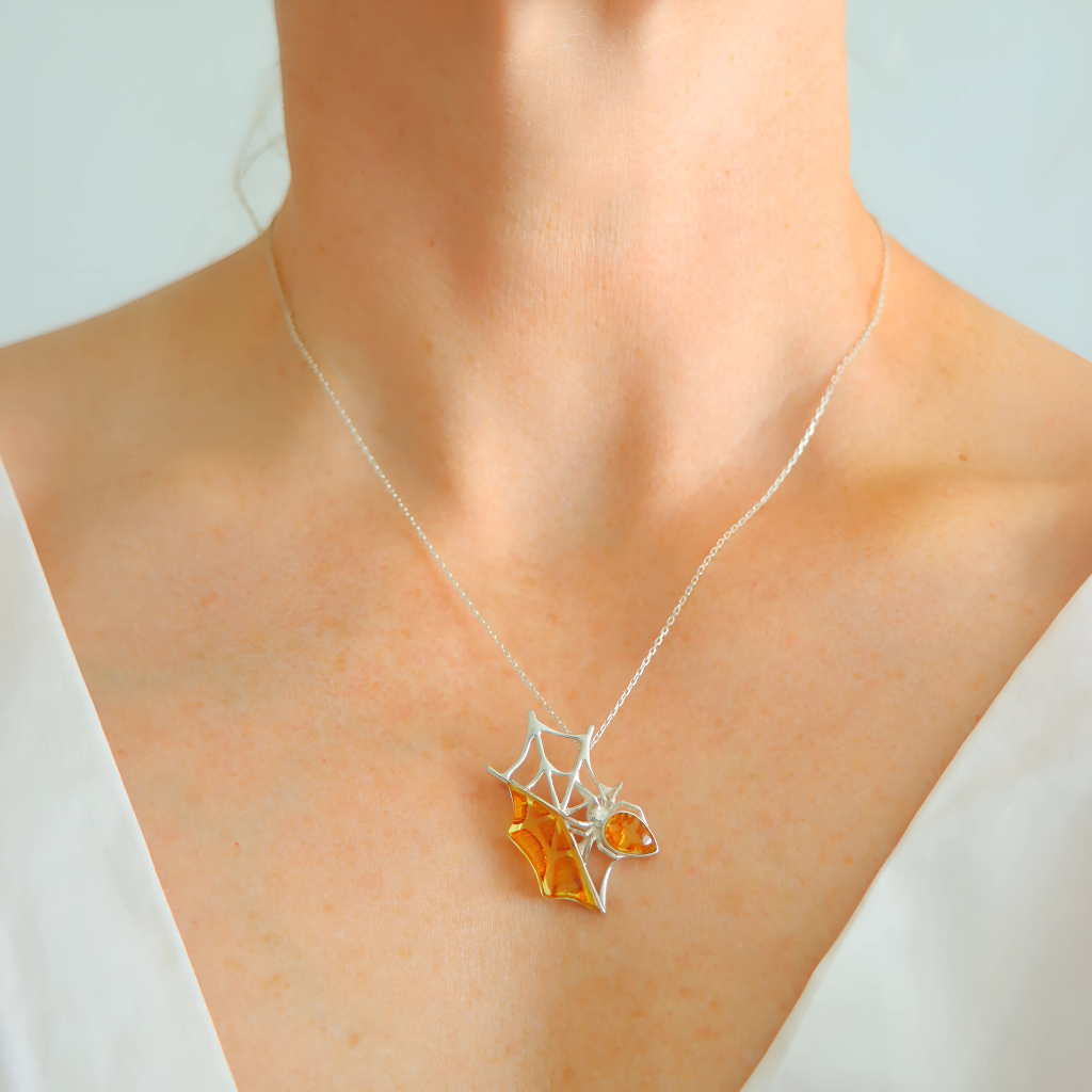 Amber Necklace with a spider web and orange gemstone pendant on a mannequin.