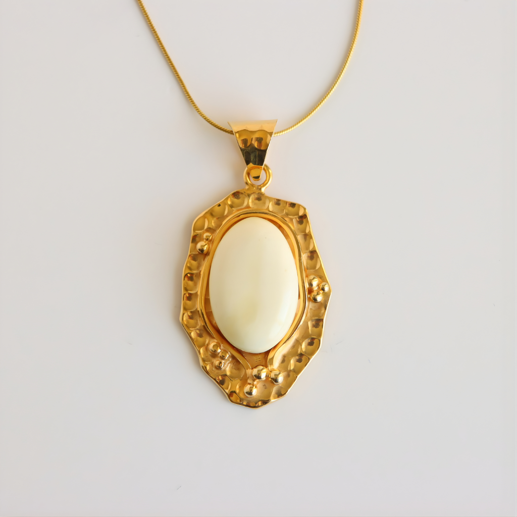 Gold pendant amber necklace with a white stone on a light gray background