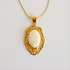 Gold pendant amber necklace with a white stone on a light gray background