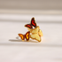 Af gold amber butterfly ring with red and yellow amber details, displayed on a clean white surface with soft shadows.