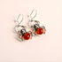 Spider-shaped sterling silver earrings with amber-colored centers on a light beige background