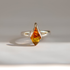 A silver amber ring featuring a marquise-cut amber gemstone, displayed on a neutral light gray background with a soft shadow.