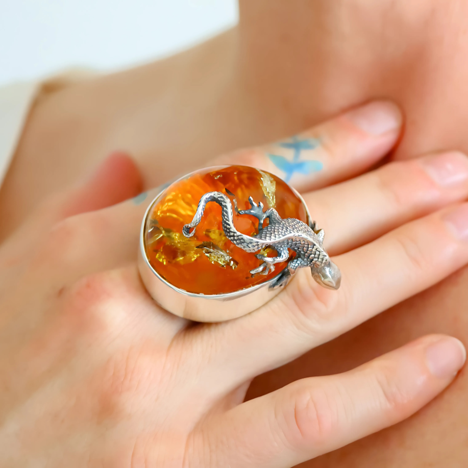 Statement ring with a lizard design on an orange stone worn on a finger