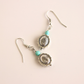 Silver western earrings with turquoise beads on a beige background