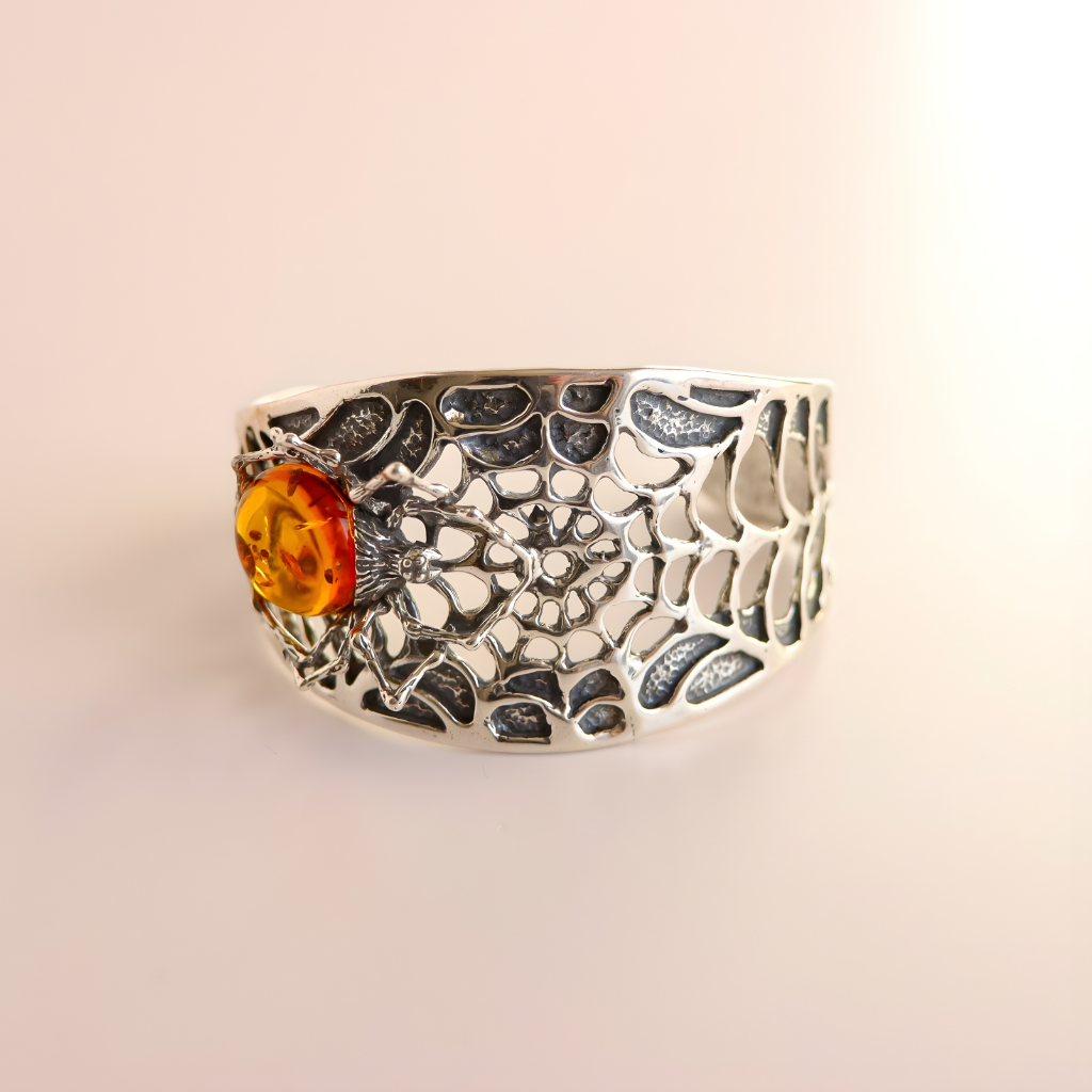 Silver amber bracelet with a central cognac amber stone on a beige background