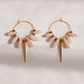 A pair of gold-tone kunzite dagger hoop earrings with dangling pale pink stone accents and a long tapered gold drop, photographed on a light neutral background.