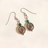 A pair of silver-toned malachite dangle earrings with green beads and circular fan-shaped charms, photographed on a plain off-white background.