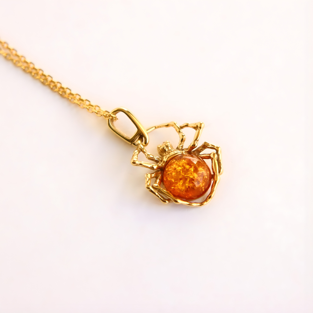 Gold amber necklace with a spider pendant featuring an amber stone on a white background