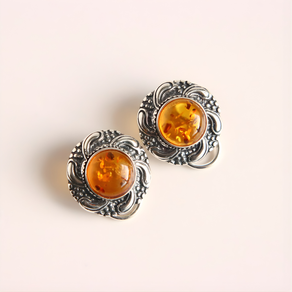Pair of silver clip on earrings with amber stones on a light background