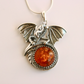 Silver dragon pendant with amber stone on a light pink background