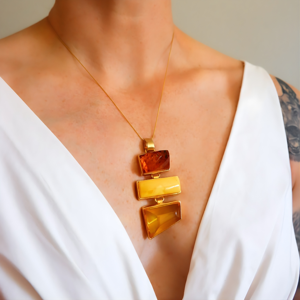 Gold statement necklace with a pendant on a person wearing a white top