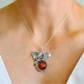 Necklace with a silver dragon pendant and amber stone worn by a person