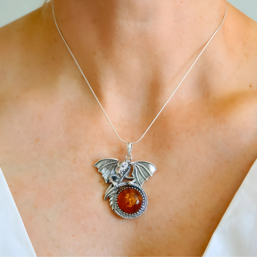 Necklace with a silver dragon pendant and amber stone worn by a person