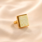Gold amber ring with a square stone on a beige background