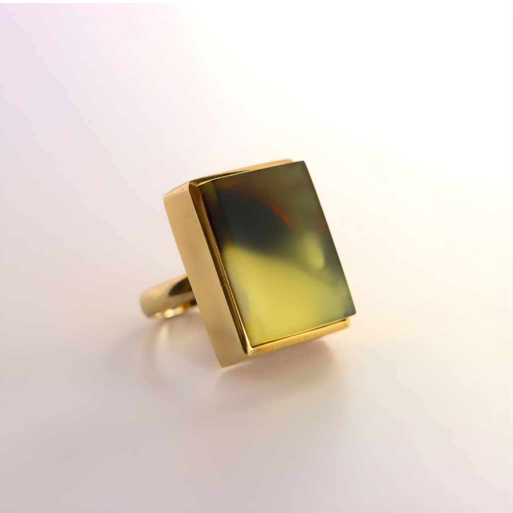 Gold amber ring with a square, multicolored stone on a light background