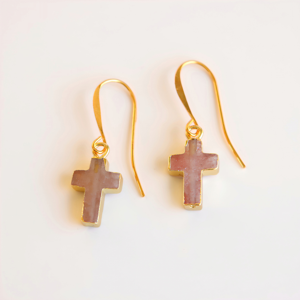 A pair of gold  rose quartz cross drop earrings with a dusty rose gemstones  displayed on a clean white background.