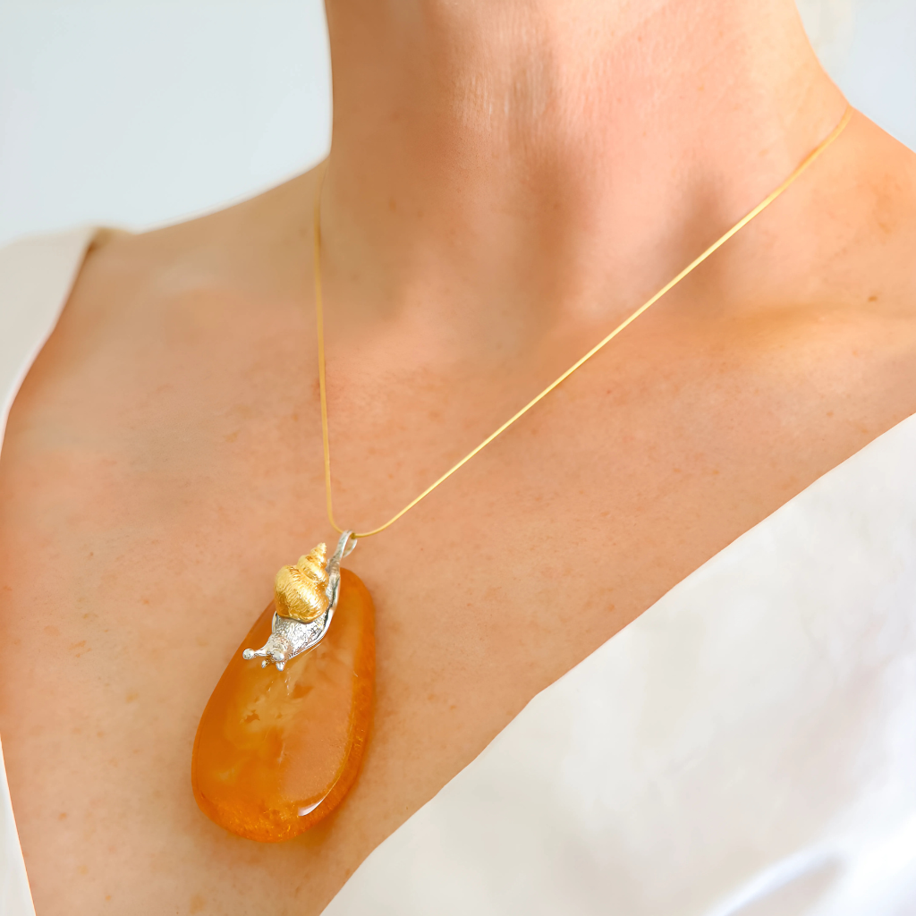 statement Necklace with an orange pendant on a person wearing a white top.