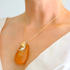 statement Necklace with an orange pendant on a person wearing a white top.