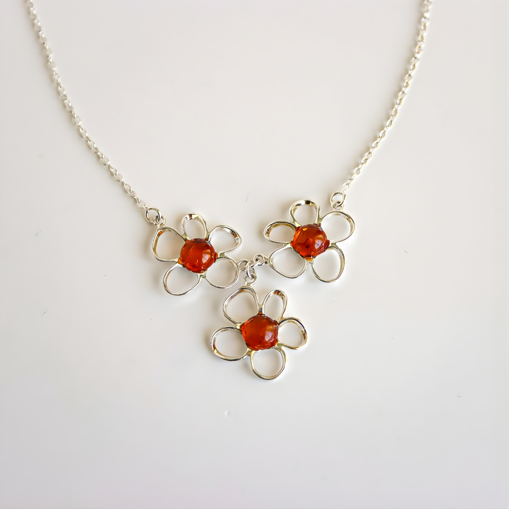 Silver amber flower necklace with flower-shaped pendants featuring red stones on a white background