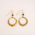 Gold hoop earrings with black beads on a beige background