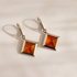 A pair of silver drop amber earrings with square amber gemstones, displayed on a clean white background with soft shadows.