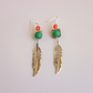 feather drop earrings with green and orange gemstone on gray background

