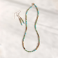 A beaded necklace and matching drop earrings laid out on a white fabric background. The jewelry features small multicolored Hubei turquoise beads with turquoise blue, green, and brown tones, suspended from silver-toned hooks.