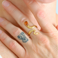Gold snake ring on a finger with a tattoo of a bear.