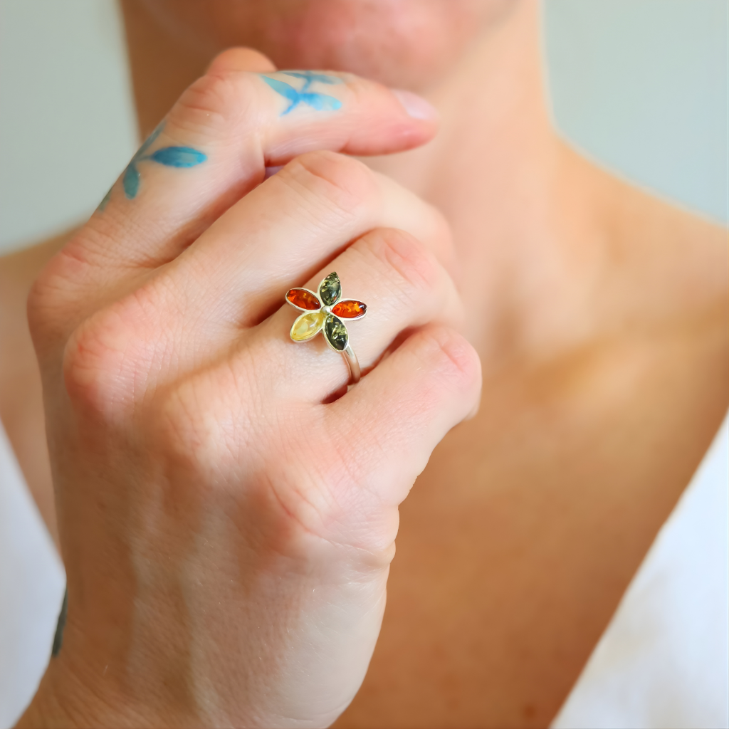 Close-up of a hand wearing a colorful amber ring with a white background