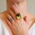 Close-up of a hand wearing a gold amber ring with a green gemstone.