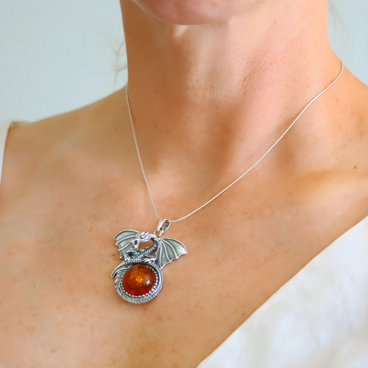 Silver dragon necklace featuring an amber stone on a person's neck.