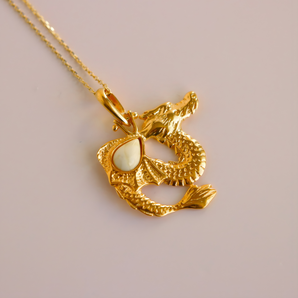Gold dragon pendant necklace on a light pink background