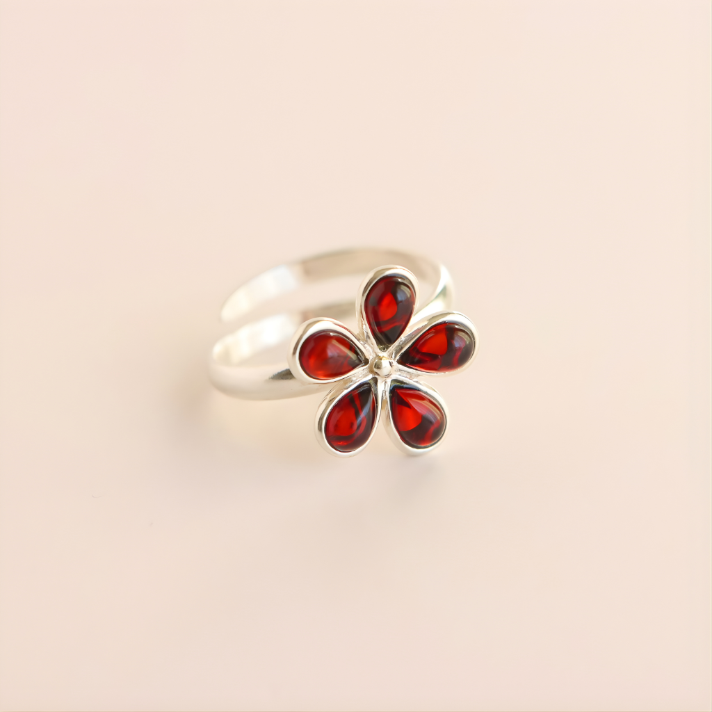 Silver amber ring with red gemstones on a beige background