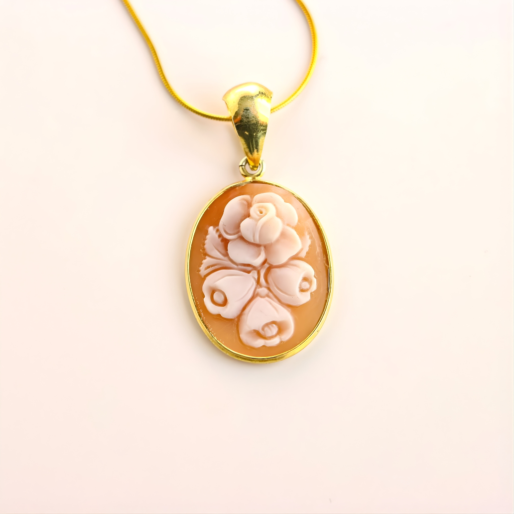 Gold flower necklace with a floral cameo pendant on a light beige background