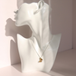 A delicate silver amber necklace with a butterfly pendant, displayed on a white ceramic female bust mannequin against a soft pink background.