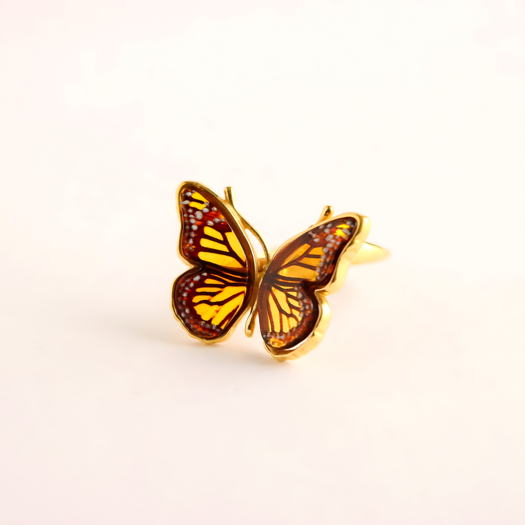 Butterfly ring with gold and amber colors on a light beige background