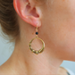 Gold hoop earring with beads worn by a person