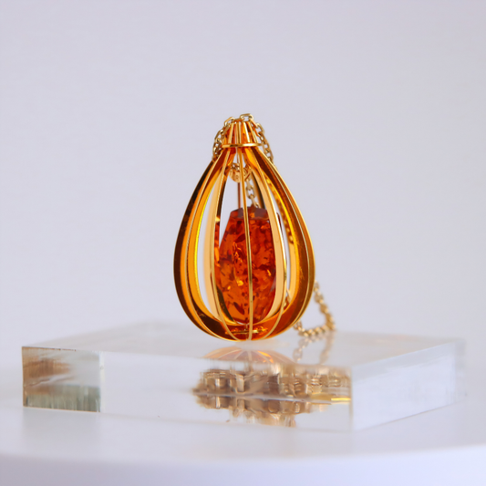 cognac colored amber necklace with gold chain on a white background