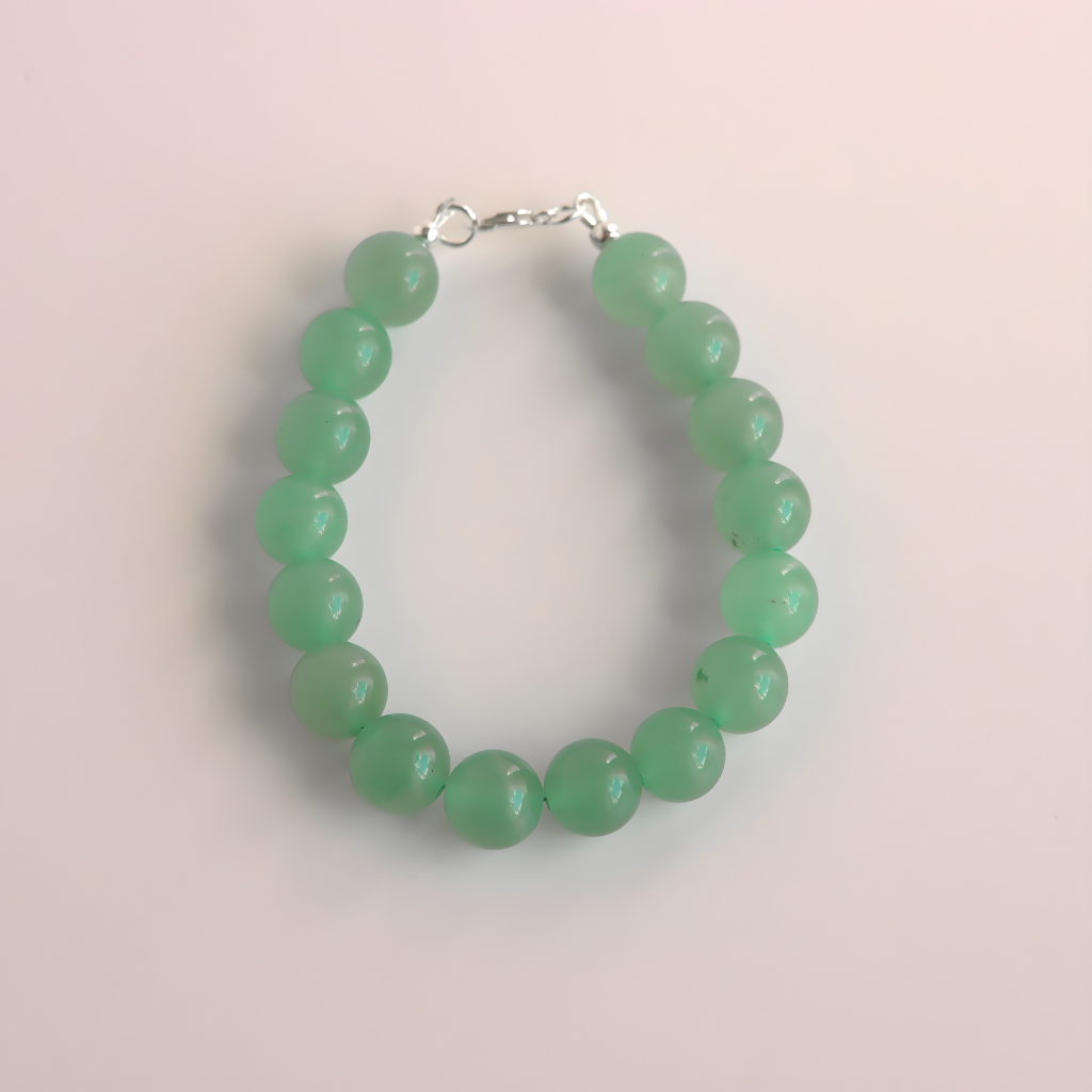 Green beaded jade bracelet on a light pink background