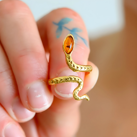 Gold snake ring with a orange gemstone on a finger