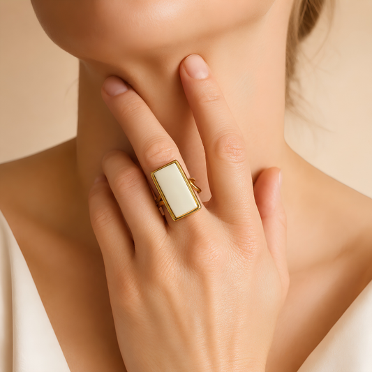 Model wearing a rectangular white amber ring in a polished gold-tone setting.