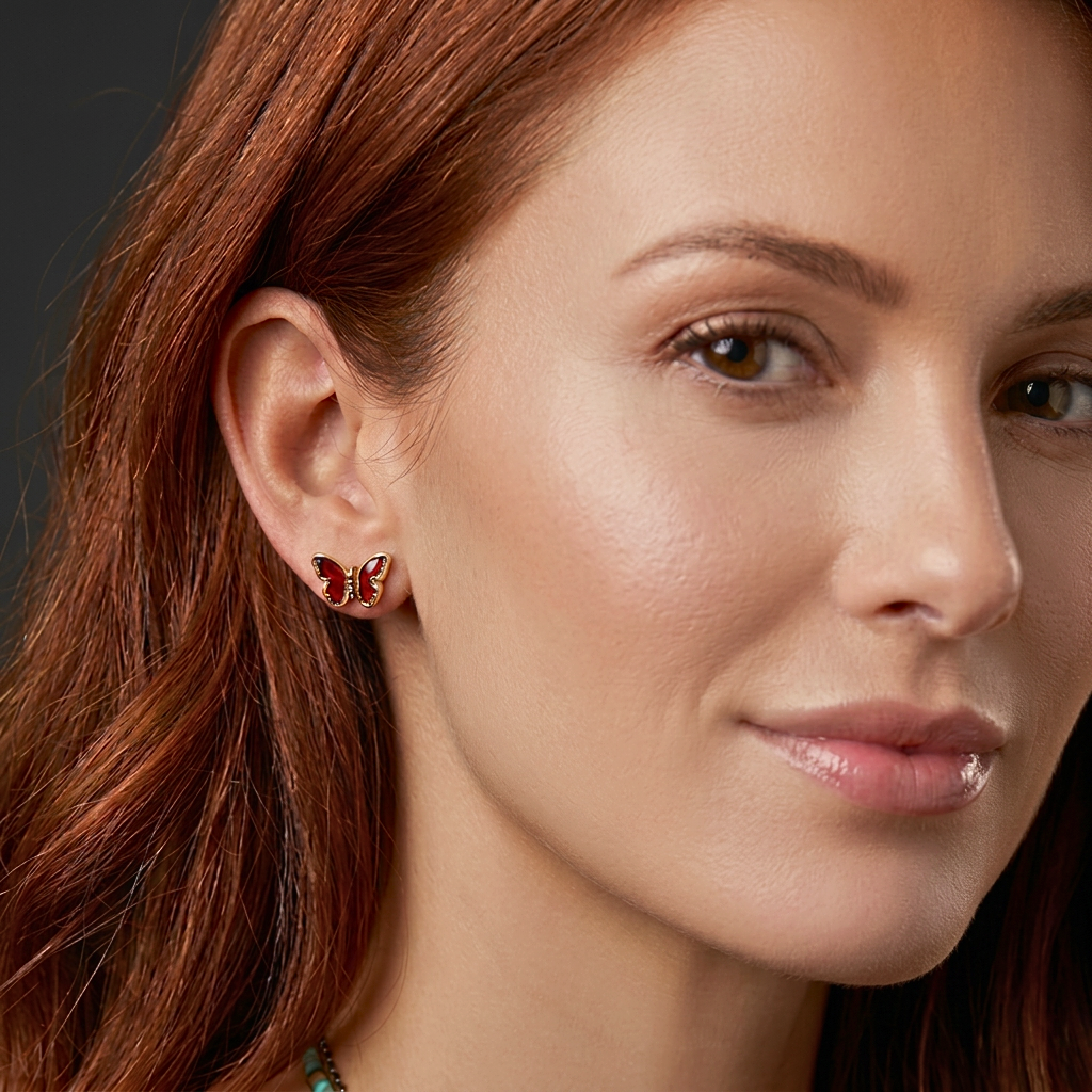 Close-up of a woman wearing butterfly gold stud earrings with a neutral background