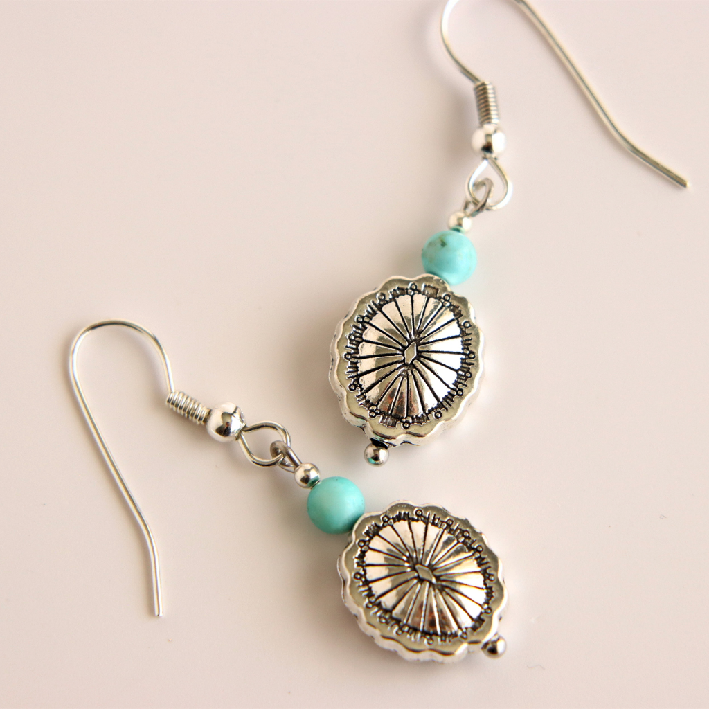 Silver western earrings with turquoise beads on a beige background
